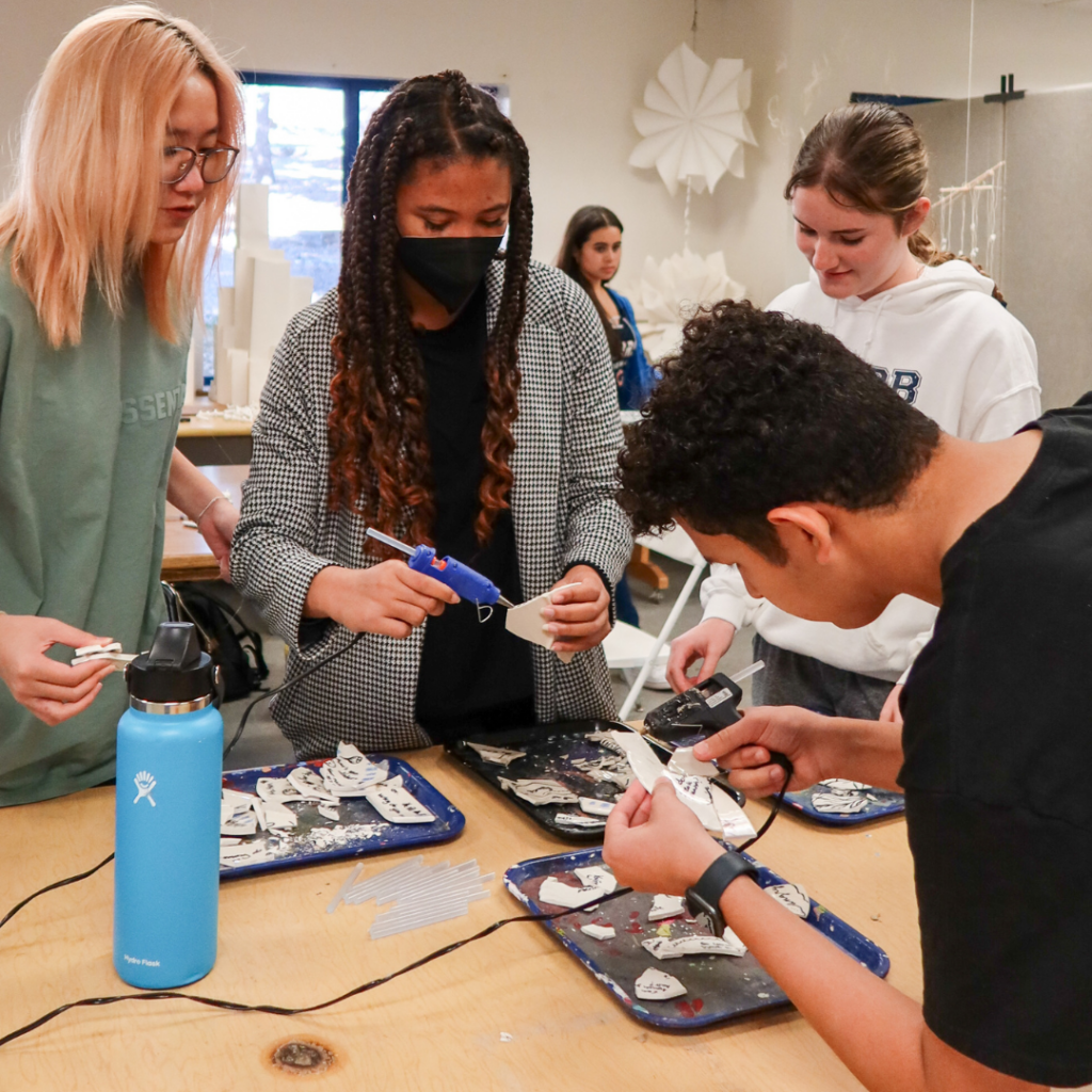 Students glue their ceramic shards together to create something new