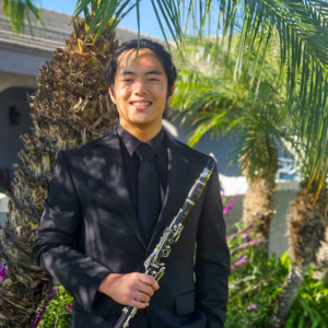 Hanbo Xu poses with his clarinet surrounded by palm trees